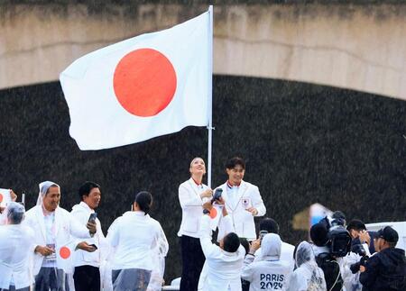 　パリ五輪の開会式で、セーヌ川をパレードする船上で日の丸を手にする日本選手団旗手の江村美咲（左）と半井重幸（代表撮影・共同）