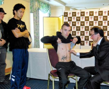 タトゥーの入った挑戦者・ジャモエ（中央）の検診を見つめる王者・山中（左）＝４月２０日、大阪