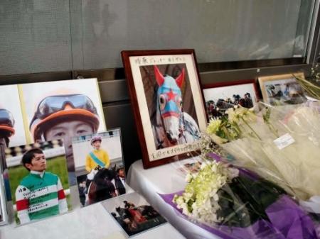 阪神競馬場パドック脇に設置された後藤騎手の献花台はファンからの写真や花であふれている