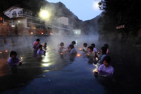 　川湯温泉の仙人風呂で竹あかりを手に湯あみする女性たち（熊野本宮観光協会提供）