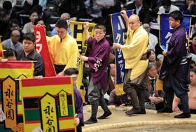 　懸賞を持って土俵をまわる呼び出しの大将（中央）＝２２日、エディオンアリーナ大阪