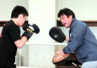 ミットを構えてボクシング部員のパンチを受ける赤井英和総監督(右)