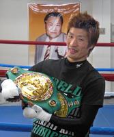 赤ちゃんを抱くようにベルトを手にする佐藤洋太