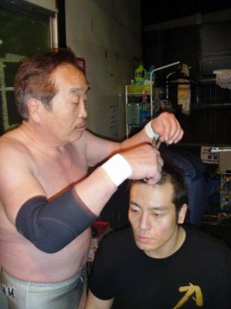 １周年の記念日に試合に敗れて断髪を決め、父・百田光雄（左）にハサミを入れてもらう力