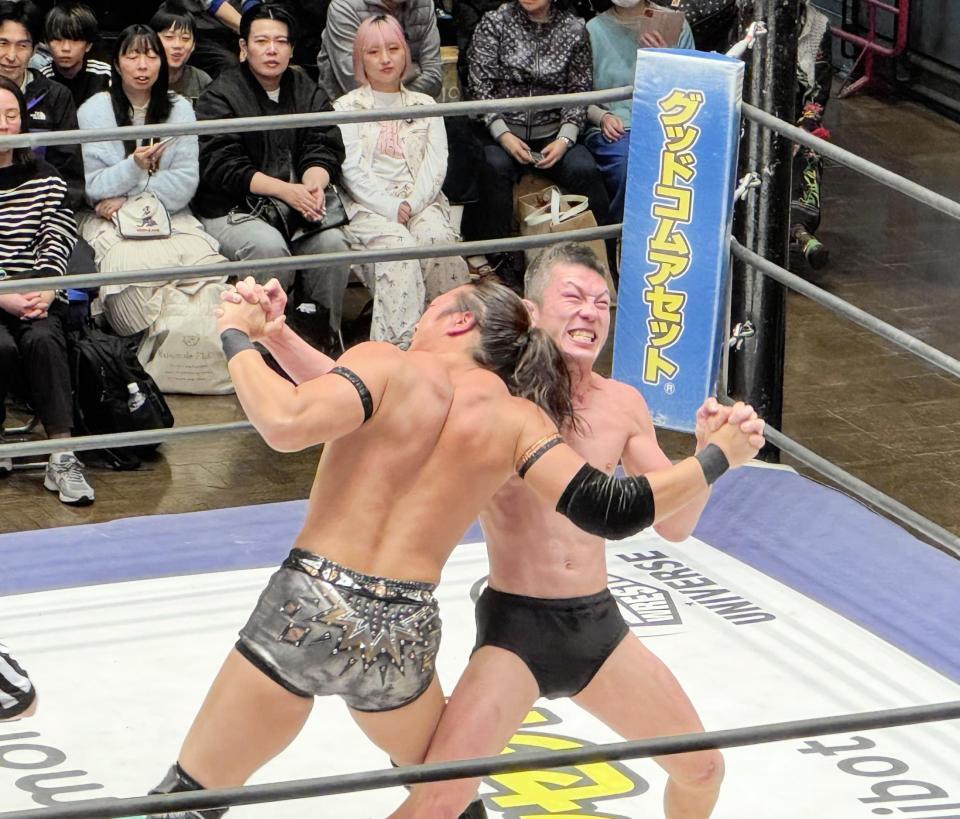 青木真也（奥）と手四つで力比べをする竹下幸之介