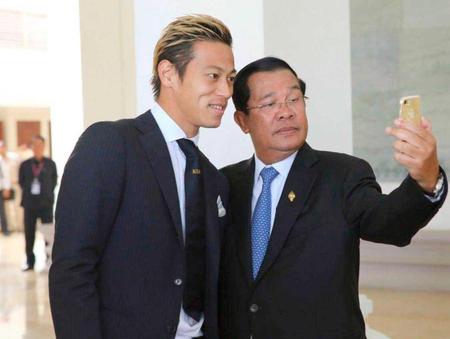 　本田（左）と一緒に、スマートフォンで自撮りをするカンボジアのフン・セン首相