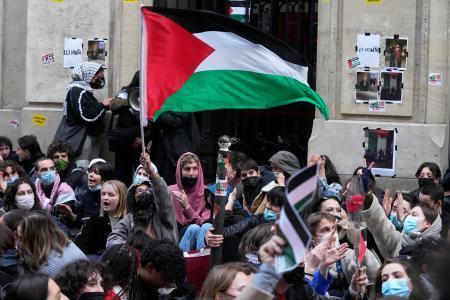 　パリ政治学院の前でパレスチナの旗を振る学生ら＝２６日、パリ（ＡＰ＝共同）
