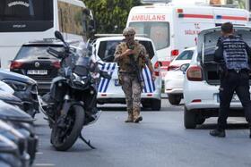 　銃撃事件の現場付近を歩く警察官ら＝７日、トルコ・イスタンブール（ロイター＝共同）