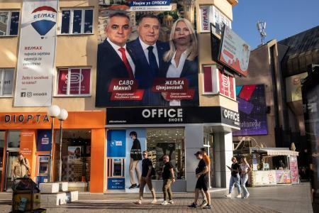 　ボスニア・ヘルツェゴビナ北部バニャルカで、総選挙の候補者が写った看板の前を通る人たち＝３日（ロイター＝共同）