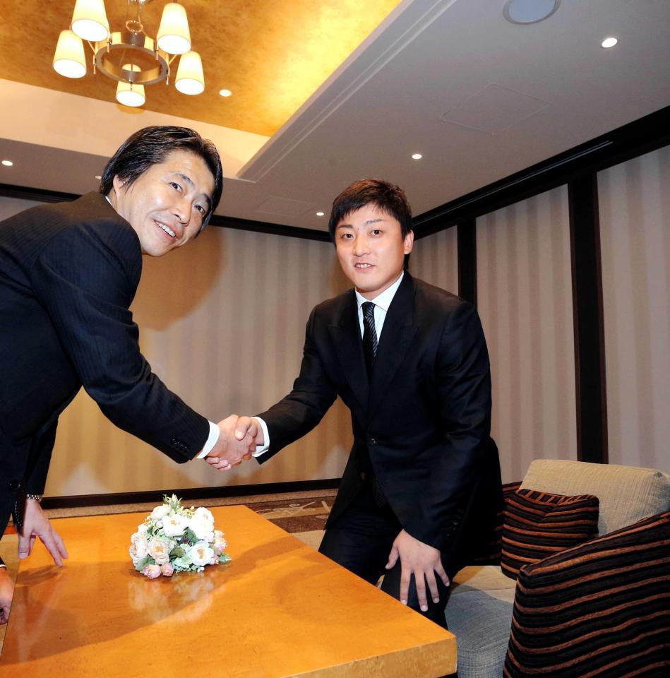 交渉の席で握手をかわす高橋聡（右）と高野球団本部長