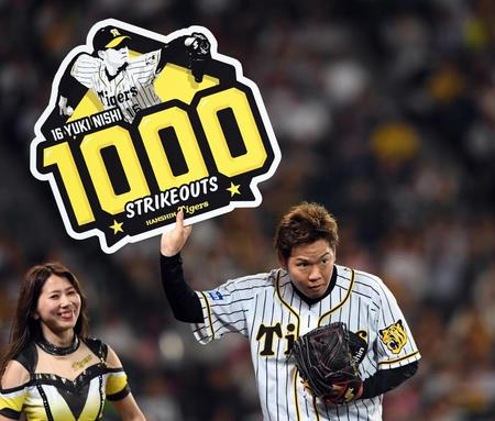 ５回、阪神・西勇輝は１０００奪三振のボードを手にファンの声援に応える＝甲子園（撮影・山口登）