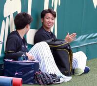 　グラウンドに座り門別（左）と話し込む村上（撮影・山口登）