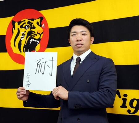 　今年の漢字「耐」を書いた色紙を手にする石井（撮影・山口登）