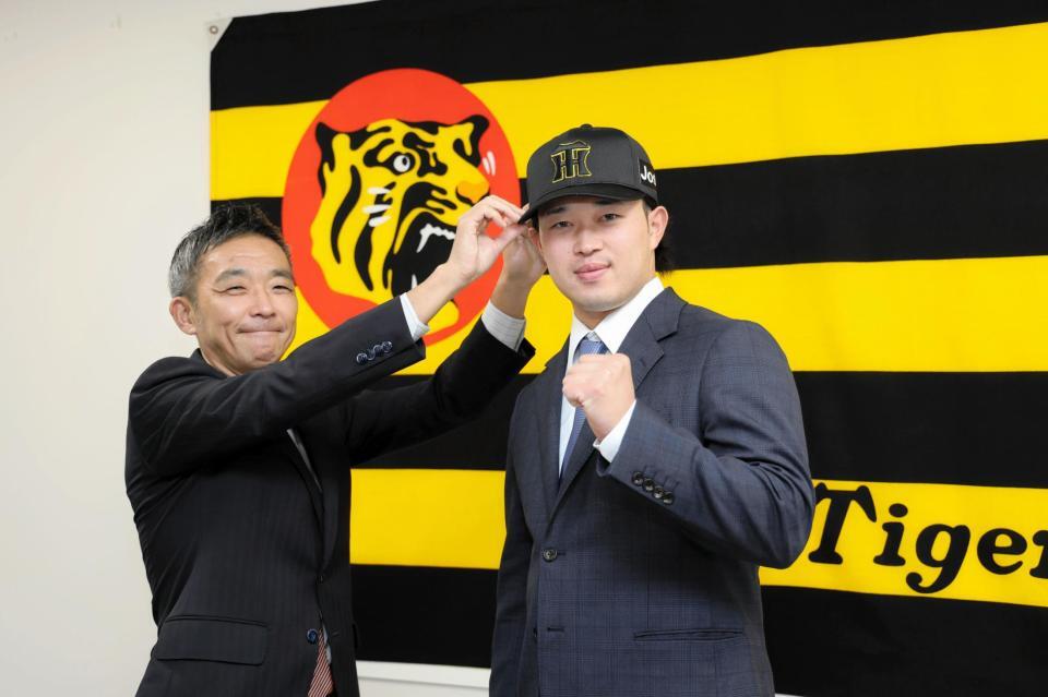 　阪神・竹内孝行球団副本部長（左）から帽子を被せてもらう浜田（撮影・山口登）