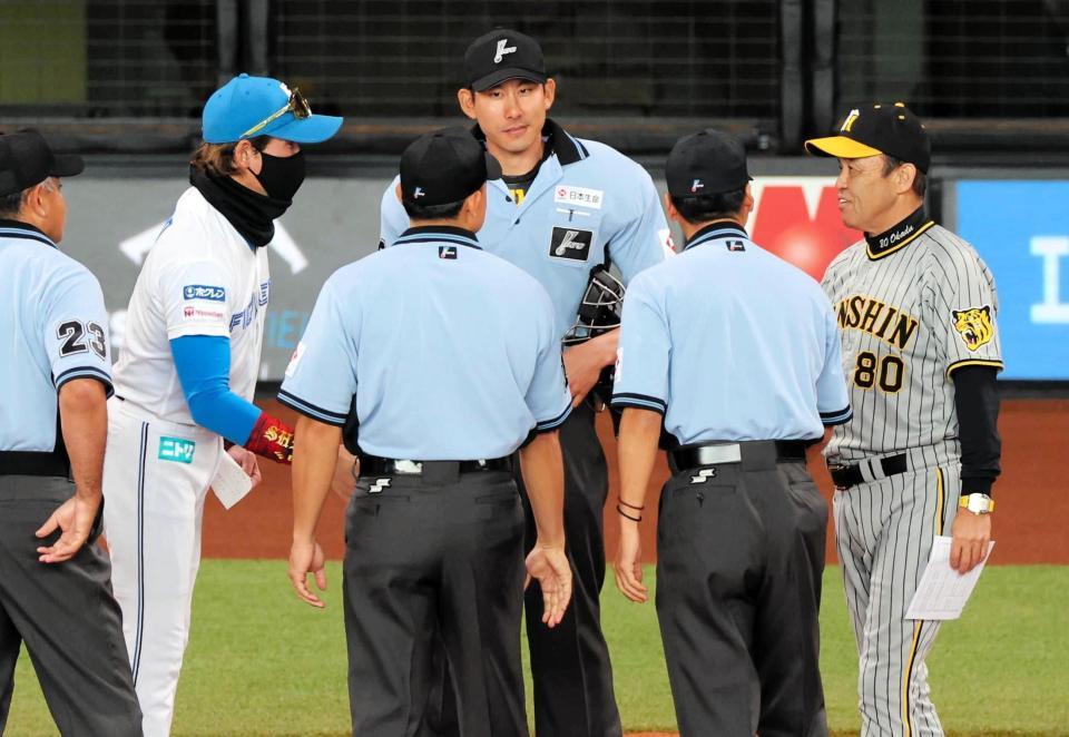 メンバー表を交換する阪神・岡田監督（右）と日本ハム・新庄監督＝６月１１日