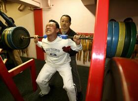 　スクワットで汗を流す金本。奥はジムの平岡代表＝２００７年１月