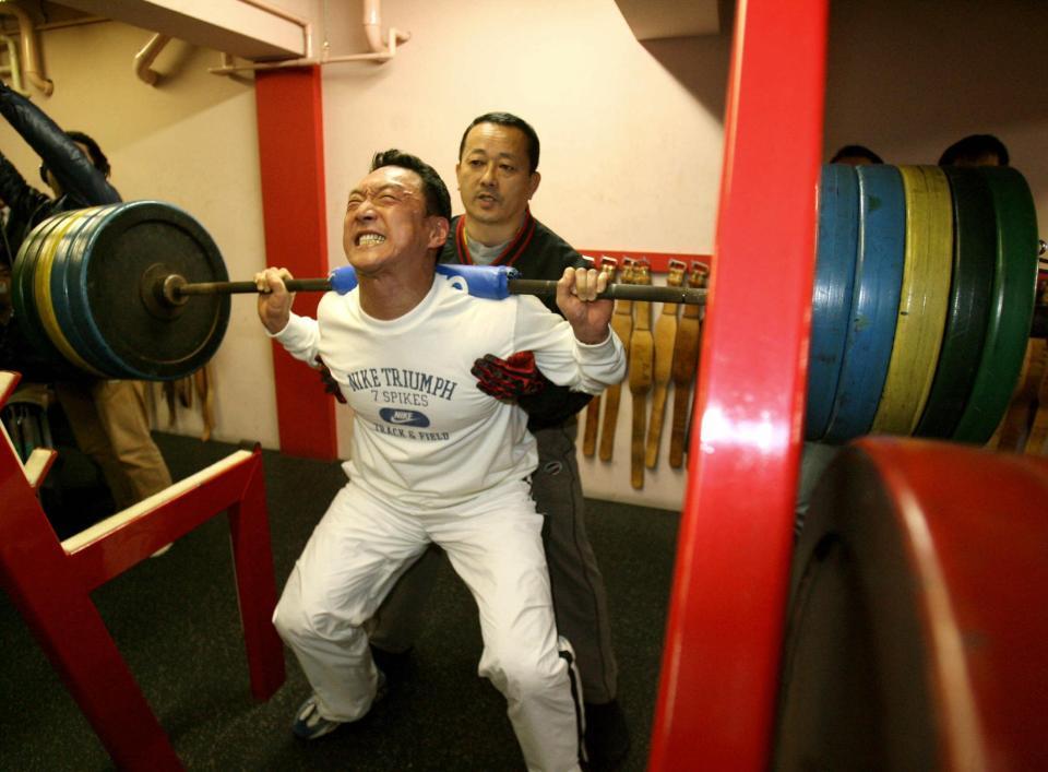 　スクワットで汗を流す金本。奥はジムの平岡代表＝２００７年１月