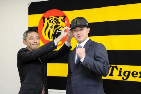 　竹内球団副本部長（左）から帽子をかぶせてもらう浜田