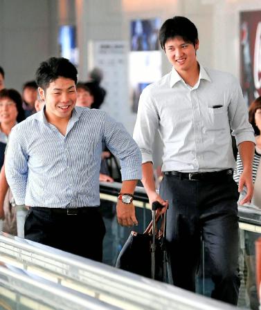 笑顔で搭乗口へ向かう日本ハムの大谷（右）。左は近藤＝羽田空港