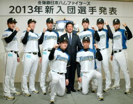 日本ハムの入団記者会見で栗山監督（中央）とポーズをとる新人８選手。前列左から渡辺、浦野、後列左から岸里、金平、岡（１人おいて）高梨、白村、石川