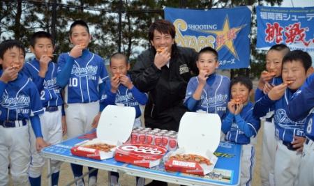 　ソフトボールチームの小学生にピザを配達し、一緒に頰張る松田（中央）