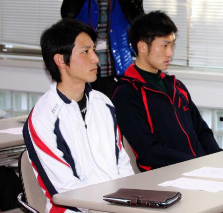 　田中の会見を真剣な表情で見つめる小林（左）
