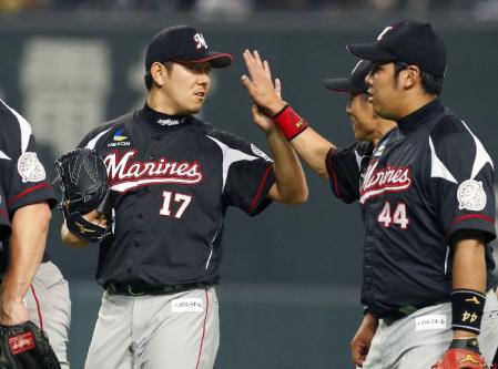 　今季初完投で３勝目を挙げ、ナインとタッチを交わすロッテ・成瀬（左）＝札幌ドーム