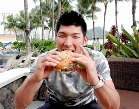 海辺でハンバーガーに食らいつく大田