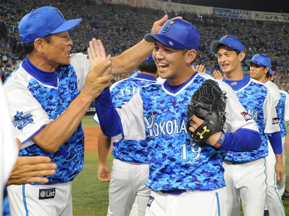 　プロ野球新人記録の３２セーブ目を挙げ、中畑監督（左）に迎えられる山崎康