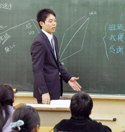 小学校を訪れ、スーツ姿で教壇に立つ秋山