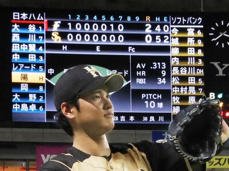 　ソフトバンク戦で、日本ハム・大谷が「１番・投手」で出場することを示すスコアボード。手前は投球練習する大谷＝ヤフオクドーム