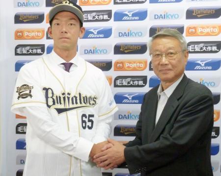 　ヤクルトからオリックスにトレード移籍し、瀬戸山隆三球団本部長（右）と握手する八木＝２１日、ほっともっと神戸