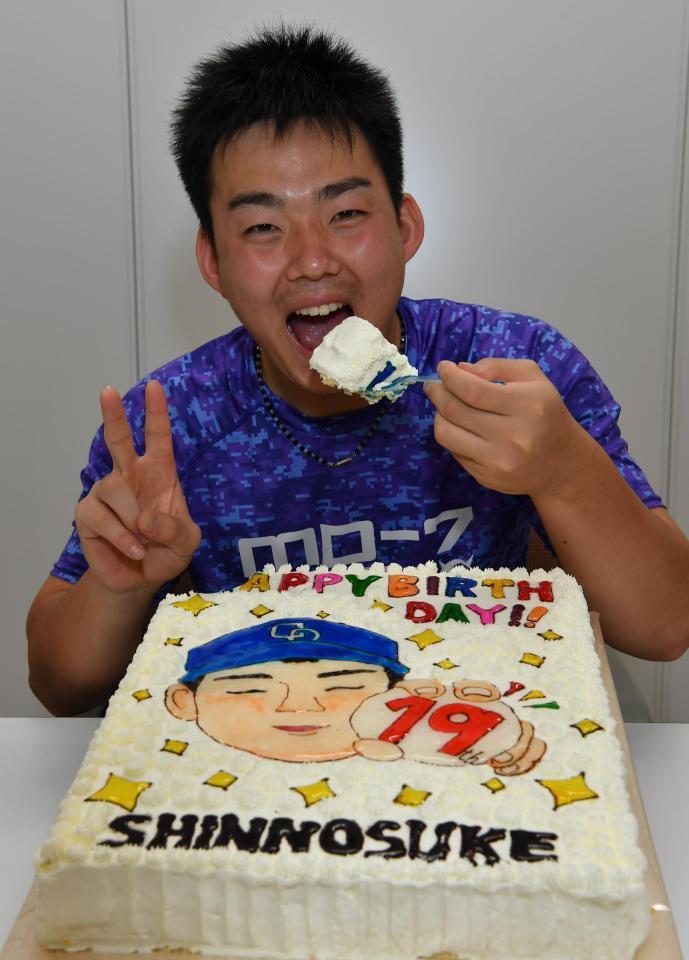 　報道陣から１９歳の誕生日ケーキを贈られ笑顔で食べる小笠原＝中日ドラゴンズ屋内練習場