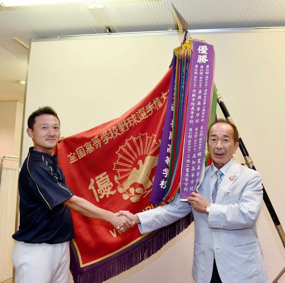 　選手権大会の優勝旗の前で小針崇宏監督（左）と握手をする山下智茂氏＝栃木県宇都宮市の作新学院（撮影・佐々木彰尚）