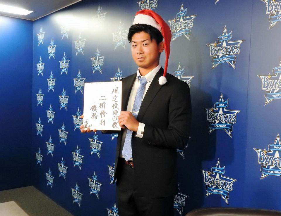来季の目標を書いた色紙を手に笑顔を浮かべるサンタ姿の今永＝横浜市内の球団事務所