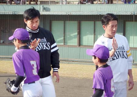　野球教室で小学生とタッチを交わすソフトバンクの長谷川（左）と川島＝１８日、熊本市