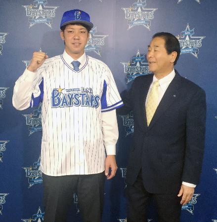 　ＤｅＮＡの入団記者会見でポーズをとる平良。右は高田繁ゼネラルマネジャー＝６日、横浜市の球団事務所