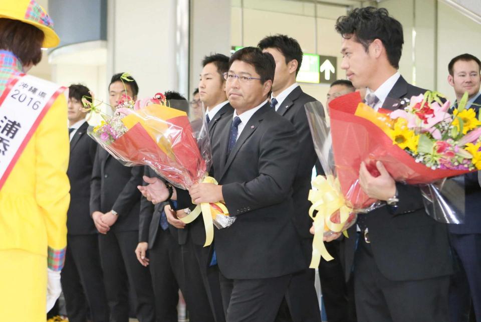 　沖縄に到着し、浦添市てだこレディから花束を受け取るの真中監督（中央）