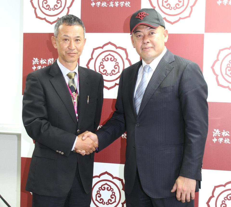 　浜松開誠館高の帽子をかぶり、佐野心監督（左）と握手する中村紀洋コーチ