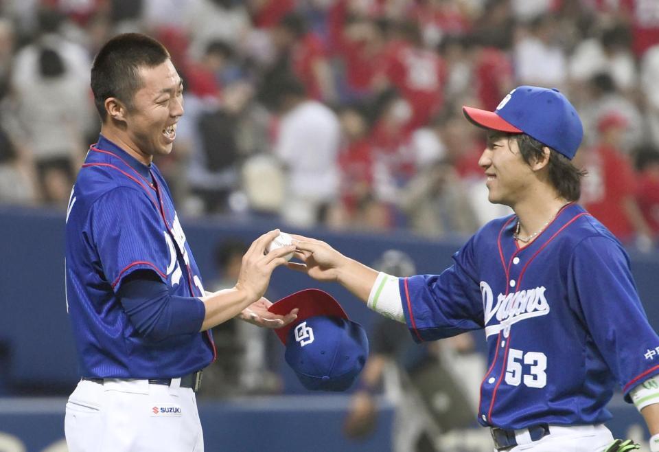 　今季初勝利を挙げ、亀沢（右）からウイニングボールを受け取る中日・吉見