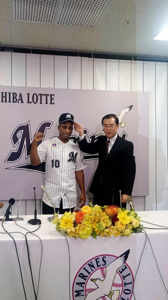 林球団本部長（右）に帽子をかぶせてもらう新入団のサントス外野手