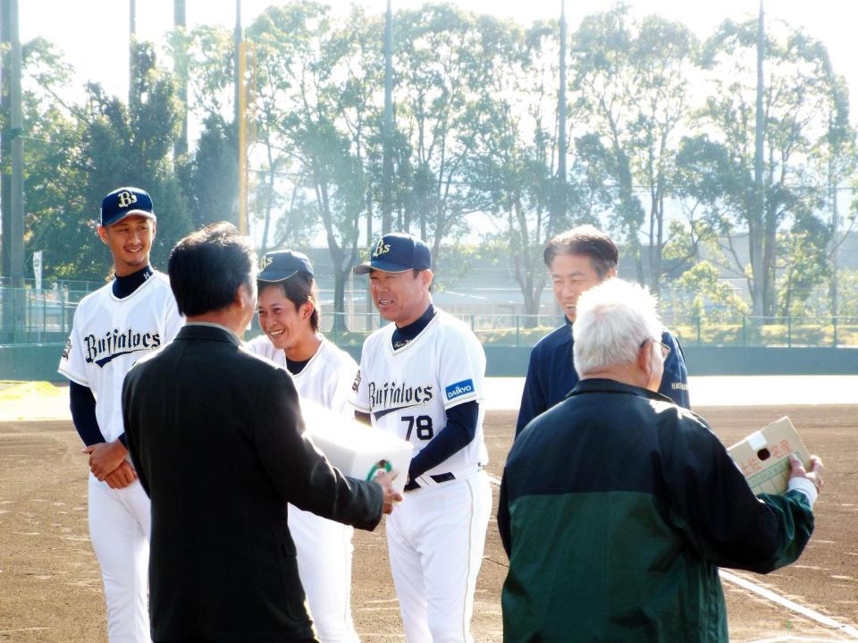記念品を笑顔で受け取る（左から）吉田一、西野、福良監督、森川球団本部長補佐