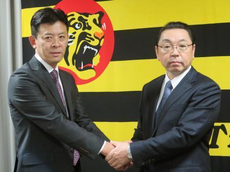 　握手を交わす阪神の四藤慶一郎球団社長（左）と後任の揚塩健治氏＝６日午後、兵庫県西宮市内の球団事務所