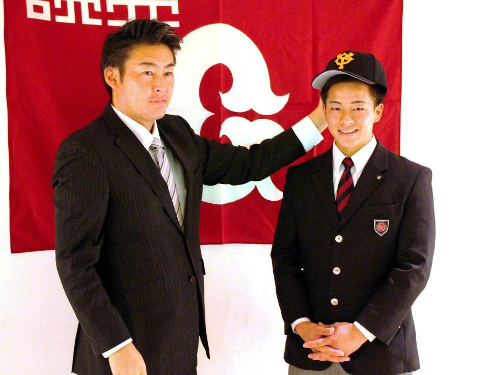 巨人と入団合意に達し、吉武スカウト（左）から帽子をかぶせてもらうドラフト８位の湯浅