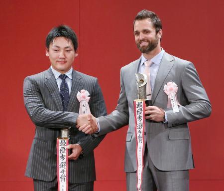 　ＭＶＰを受賞し、握手を交わす広島の丸佳浩外野手（左）とソフトバンクのデニス・サファテ投手＝２０日、東京都内のホテル