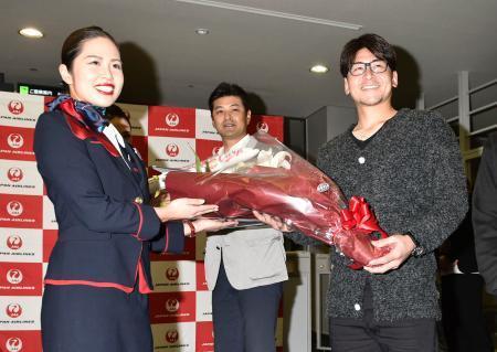 　優勝旅行の出発セレモニーで花束を受け取る広島・会沢（右）。中央は緒方監督＝１日、広島空港