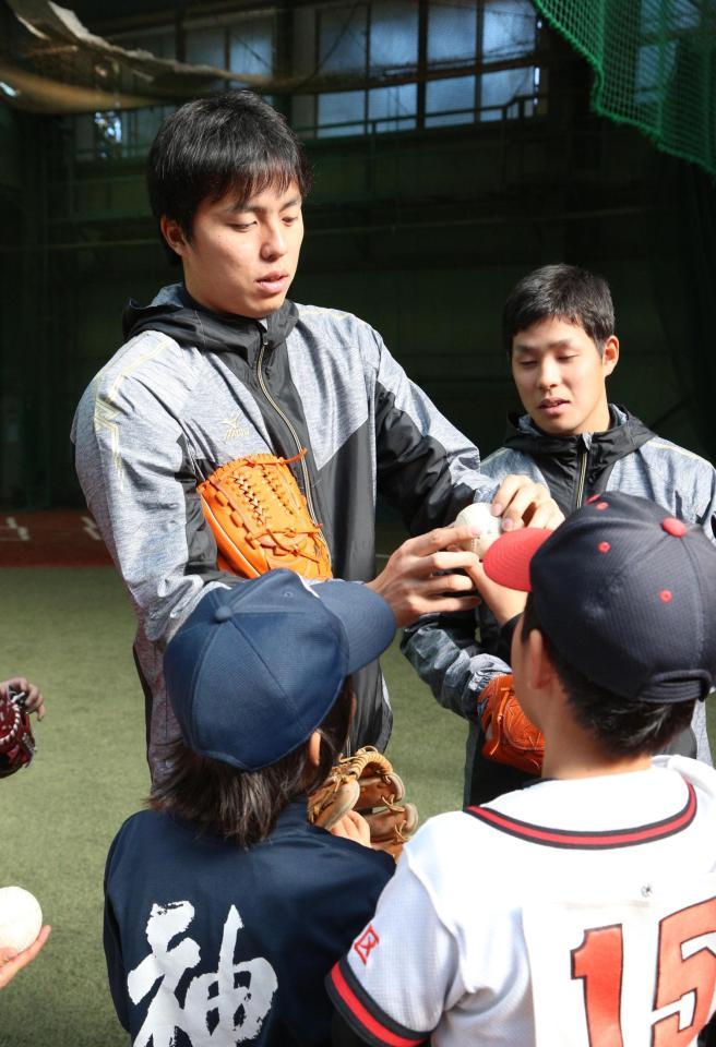 　子どもたちにボールの握りを教える田中正義