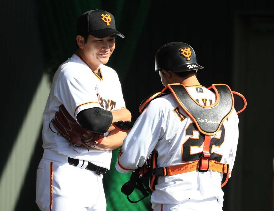 　ブルペンでの投球後、小林（右）と話をする菅野