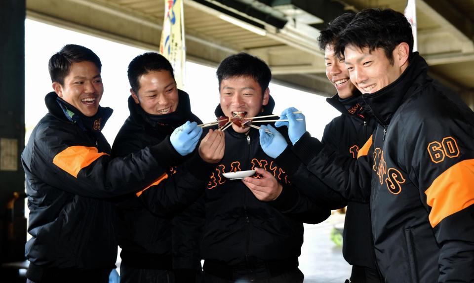 巨人・岸田行倫（中央）にカツオを食べさせる（左から）田中俊太、北村拓己、大城卓三、若林晃弘＝宮崎中央卸売市場（撮影・西岡正）