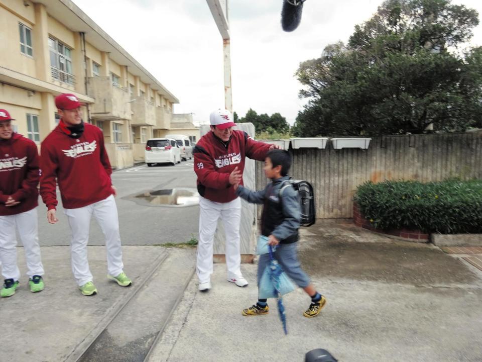 登校してきた児童をハイタッチで迎える梨田監督＝久米島小学校